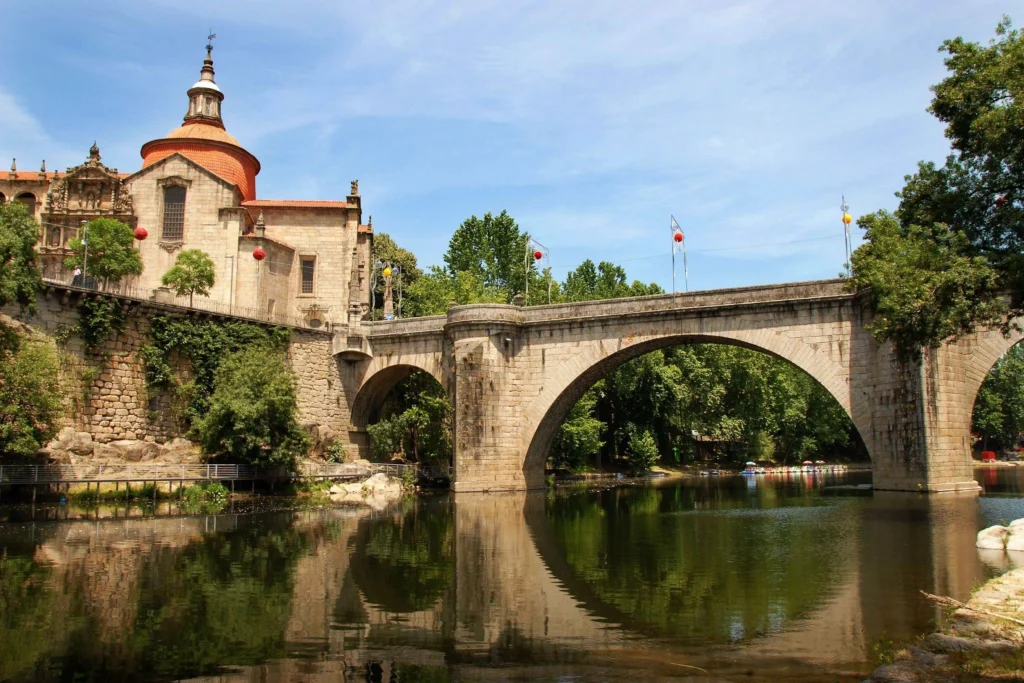 Photographie de la ville d'Amarante au Portugal, longée par le fleuve Tâmega. Le pont et l'église São Gonçalo se reflètent dans l'eau.