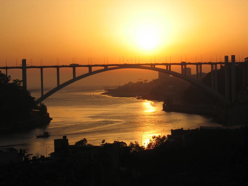 Photographie du coucher de soleil depuis les jardins du Palais de Cristal à Porto au Portugal, avec au centre le pont de l'Arrabida. 